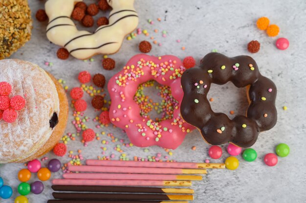 Donuts decorados glacê e granulado na vista superior de superfície branca