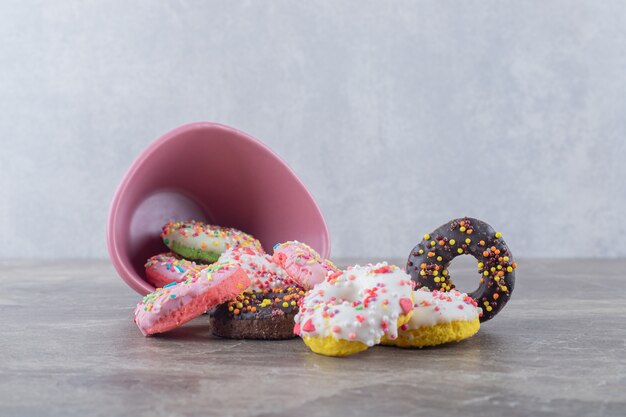 Donuts derramado de uma tigela na superfície de mármore