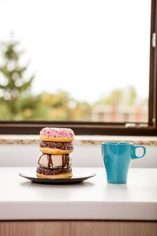 Donuts e uma xícara de café ao lado do parapeito da janela. comida deliciosa junck