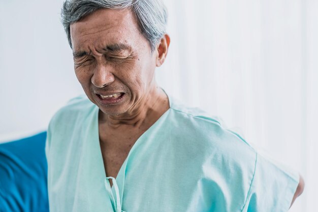 Dor e dor nas costas velho avô asiático sênior em uniforme de paciente sofre de conceito de ideias de saúde de problemas corporais