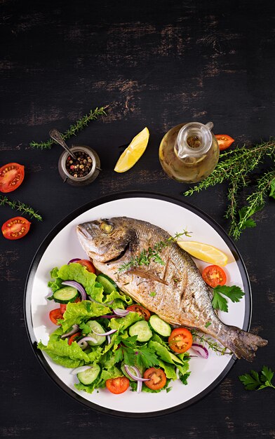 Dorado de peixe assado com limão e salada fresca em chapa branca