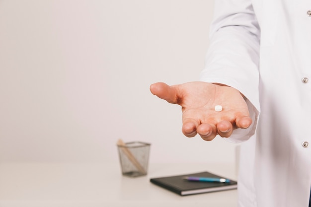Doutor com uma pílula na palma das mãos