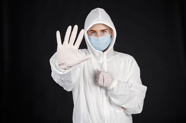 Doutor em uma máscara médica. tema coronavirus. isolado sobre a parede preta. mulher em uma roupa de proteção.