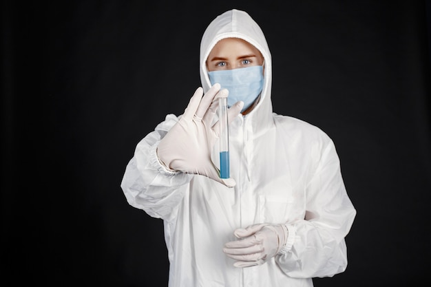 Doutor em uma máscara médica. Tema Coronavirus. Isolado sobre a parede preta. Mulher em uma roupa de proteção.