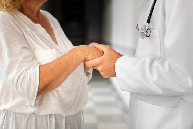 Doutor mãos segurando as mãos da mulher sênior