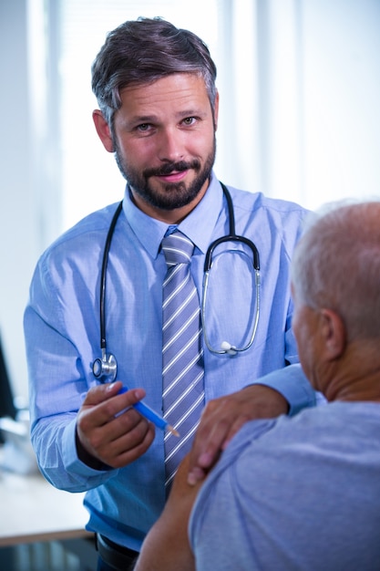 Doutor masculino que dá uma injeção a um paciente no hospital