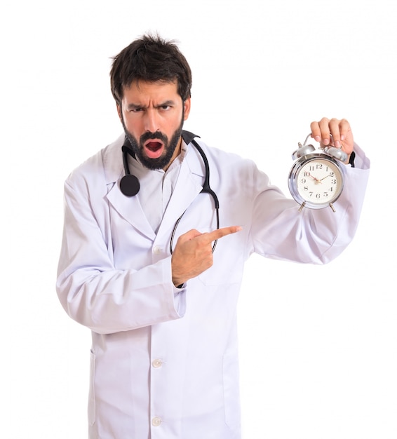 Doutor surpreso segurando um relógio sobre fundo branco
