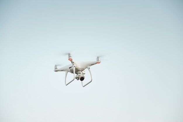 Drone branco pairando em um céu azul brilhante