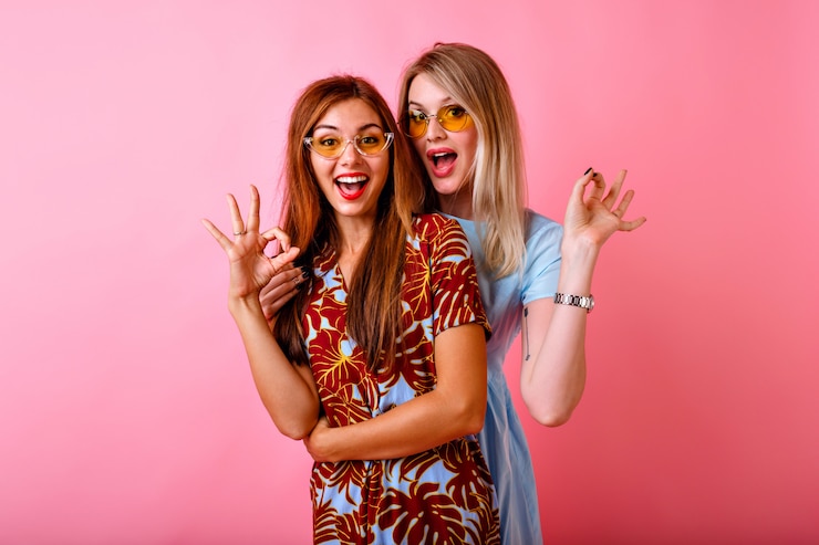 Foto grátis duas adoráveis mulheres jovens e felizes se divertindo juntas mostrando um gesto de ok