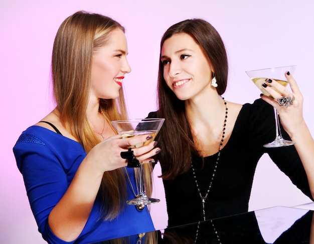 Duas amigas alegres com cocktails coloridos