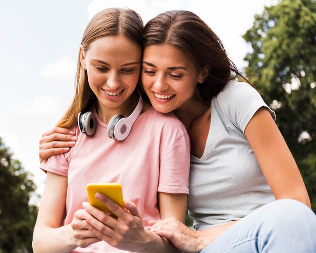 Duas amigas ao ar livre com smartphone e fones de ouvido