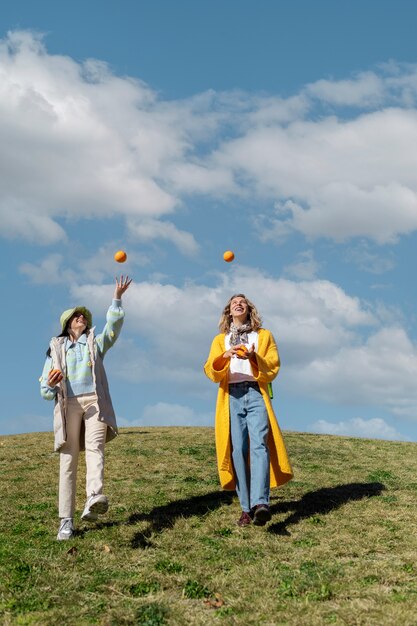 Duas amigas brincando com laranjas em um campo ao ar livre