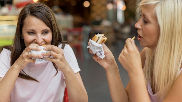 Foto grátis duas amigas comendo hambúrgueres com batatas fritas em restaurante