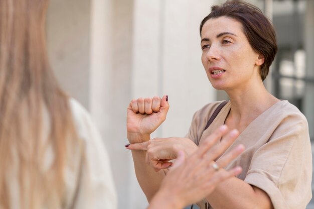 Duas amigas conversando ao ar livre usando linguagem de sinais