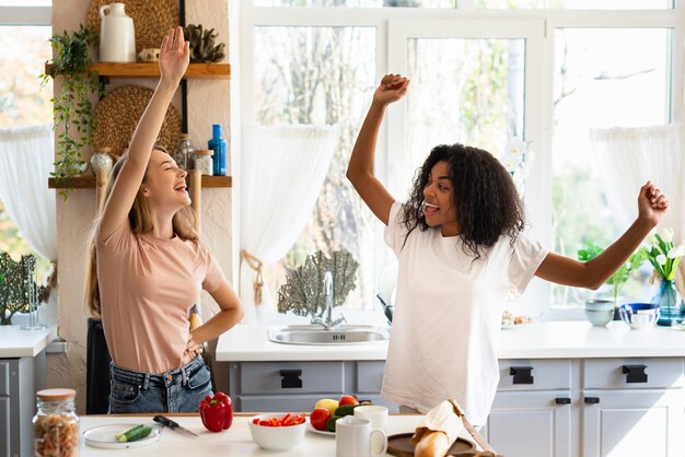 Duas amigas dançando enquanto cozinham na cozinha