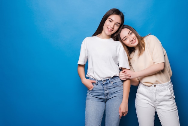 Duas amigas felizes isoladas na parede azul