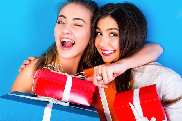 Duas amigas lindas segurando brilhantes presentes de Natal