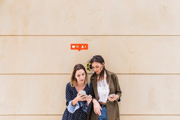 Foto grátis duas amigas olhando para notificação de gostos e comentários no celular