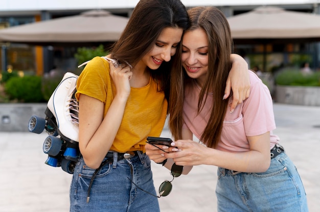 Duas amigas passando um tempo juntas ao ar livre carregando patins