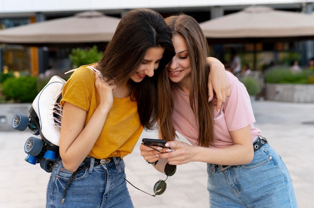 Foto grátis duas amigas passando um tempo juntas ao ar livre carregando patins