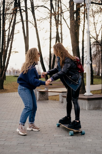 Duas amigas se divertindo andando de skate no parque