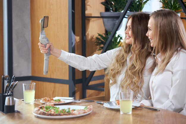 duas belas jovens blogueiras sorrindo fazendo selfie