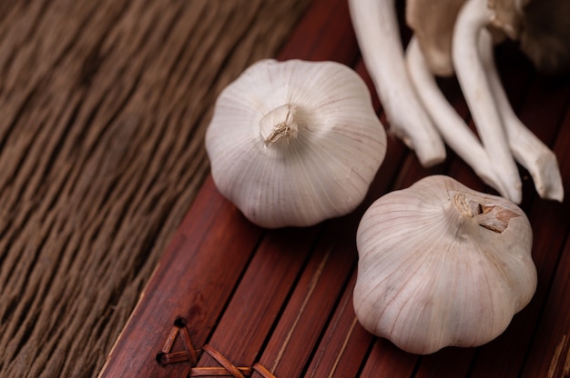 Duas cabeças de alho em ripas de madeira e um cogumelo fada