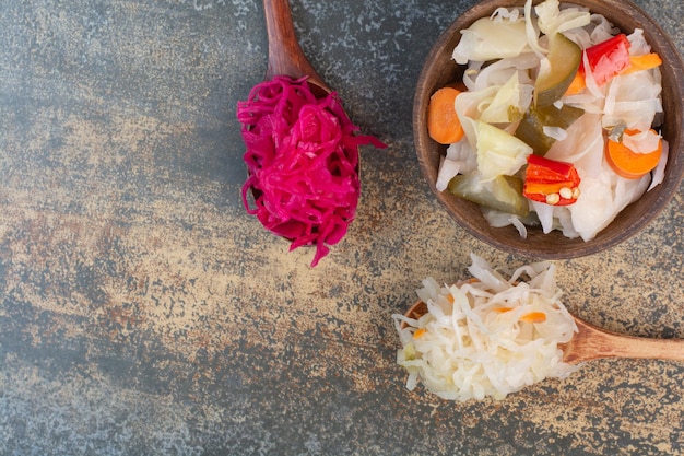 Duas colheres de repolho com uma tigela de madeira de legumes salgados. foto de alta qualidade