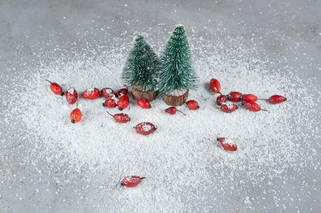 Duas estatuetas de árvore de Natal e um monte de quadris em pó de coco na superfície de mármore