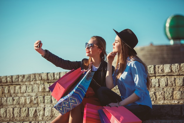 Foto grátis duas garotas andando com sacolas de compras nas ruas da cidade em dia de sol