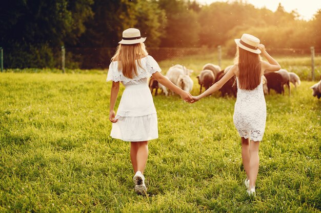 Duas garotas bonitas em um campo com uma cabras