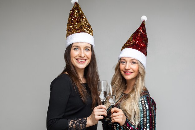 Duas garotas com gorros de Papai Noel com bebidas alcoólicas.