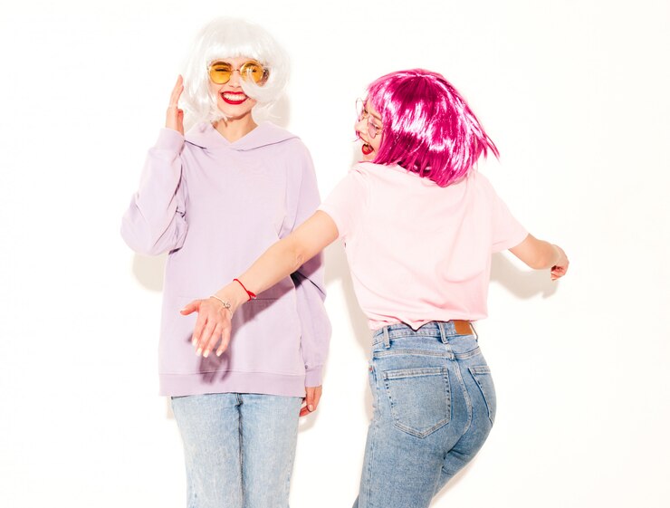 Foto grátis duas garotas hipster sorridentes sexy jovem em perucas e lábios vermelhos. belas mulheres na moda em roupas. modelos despreocupados posando perto de parede branca no estúdio enlouquecendo e dançando