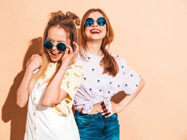 Duas garotas loiras hipster sorrindo lindas jovens em roupas de camiseta colorida na moda verão.