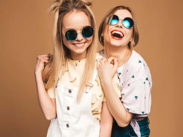 Duas garotas loiras hipster sorrindo lindas jovens em roupas de camiseta colorida na moda verão.