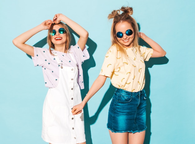 Duas garotas loiras hipster sorrindo lindas jovens em roupas de camiseta colorida na moda verão.