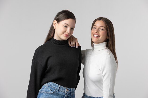 Duas garotas vestindo camiseta preta e branca posando no estúdio