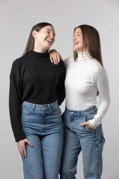 Duas garotas vestindo camiseta preta e branca posando no estúdio