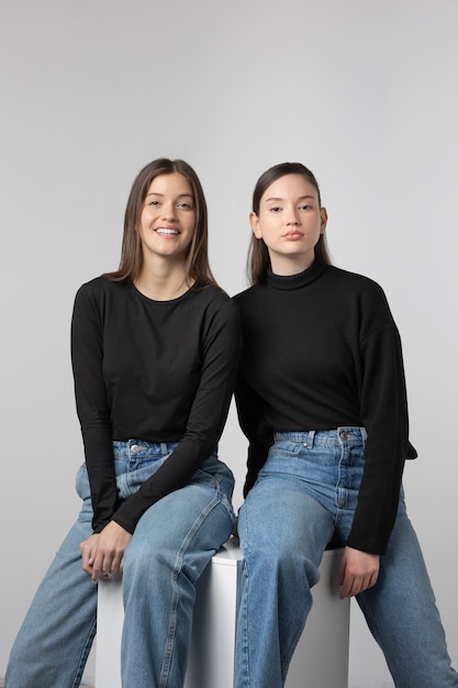 Duas garotas vestindo camiseta preta posando no estúdio