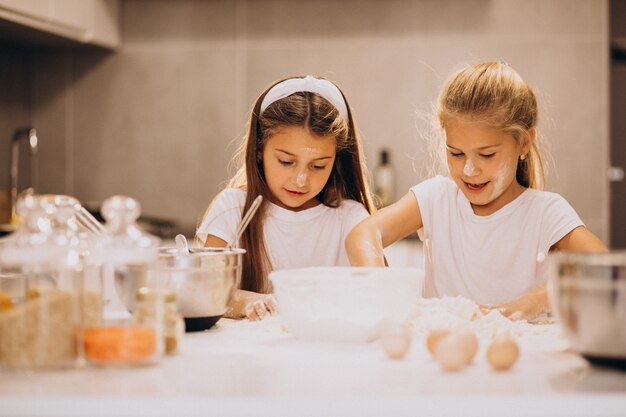 Duas irmãs meninas cozinhando na cozinha