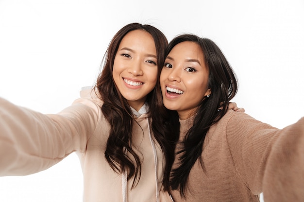 Duas irmãs positivas felizes asiáticas das senhoras