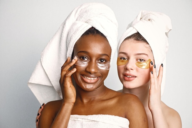 Duas jovens adolescentes com tapa-olhos nos rostos têm um cabelo enrolado em toalhas