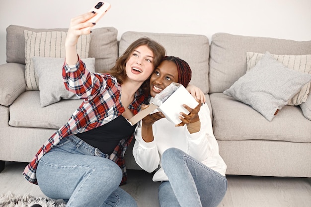 Duas jovens adolescentes sentadas no chão perto do treinador e fazem uma selfie