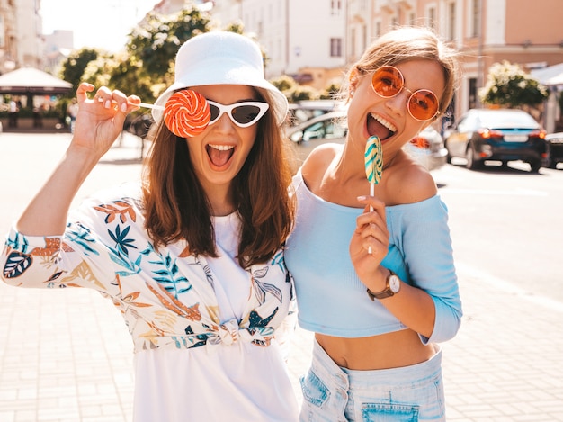 Duas jovens bonitas hipster garotas sorridentes em roupas da moda verão e chapéu Panamá.