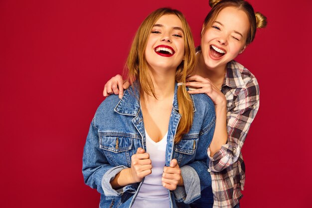 Duas jovens bonitas loiras sorrindo hipster mulheres posando em roupas de camisa quadriculada na moda verão