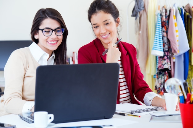 Duas jovens empresárias trabalhando com laptop em seu escritório.