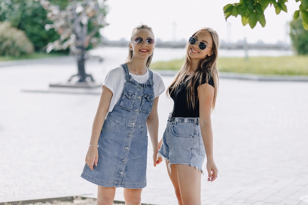 Duas jovens garotas bonitas em uma caminhada no parque. um dia ensolarado de verão, alegria e amizades.