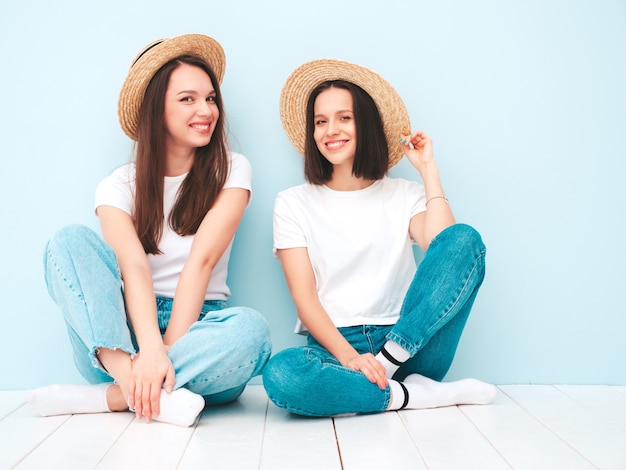 Duas jovens lindas sorrindo hipster feminina em uma camiseta branca da moda de verão e roupas jeans