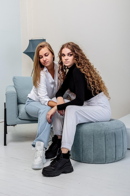 Duas jovens mulheres bonitas em calças e suéter, em botas de couro em seus pés. nova coleção de botas femininas Foto Premium