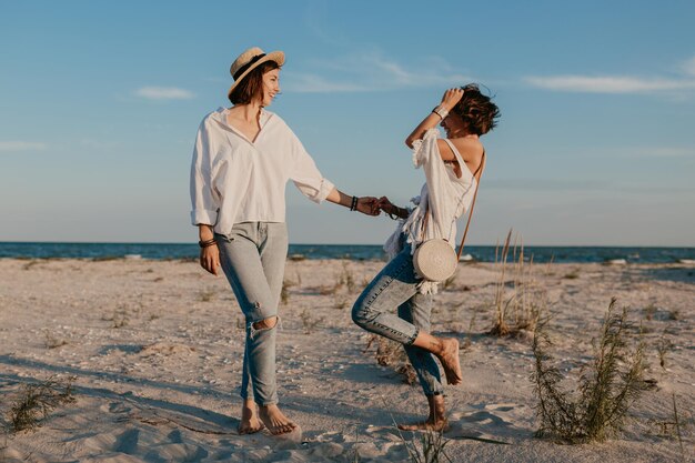 Duas jovens se divertindo na praia do pôr do sol